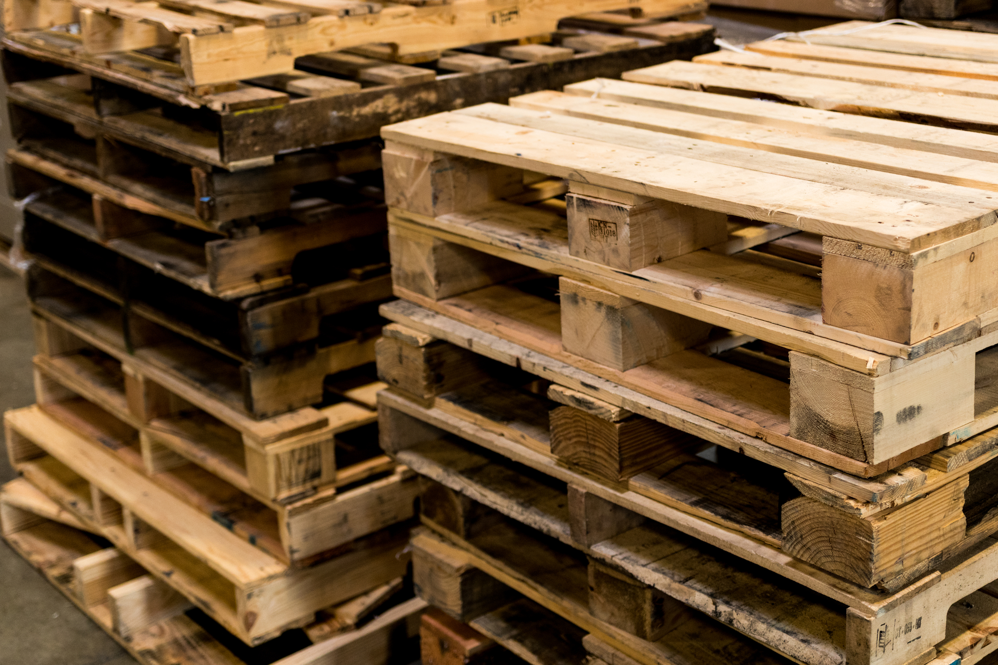 Used and new wood pallets stacked in rows cropped
