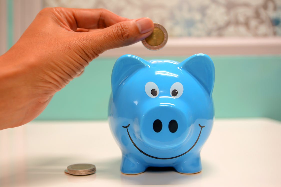 a person putting money in a blue piggy bank