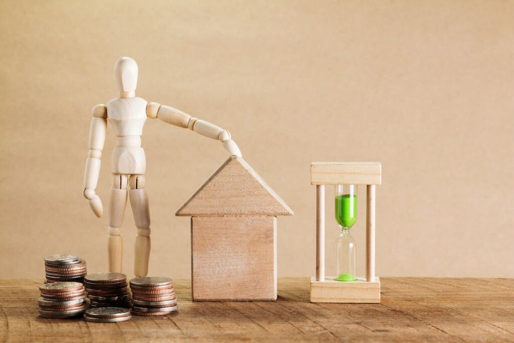 A model of a person and a house next to some coins.