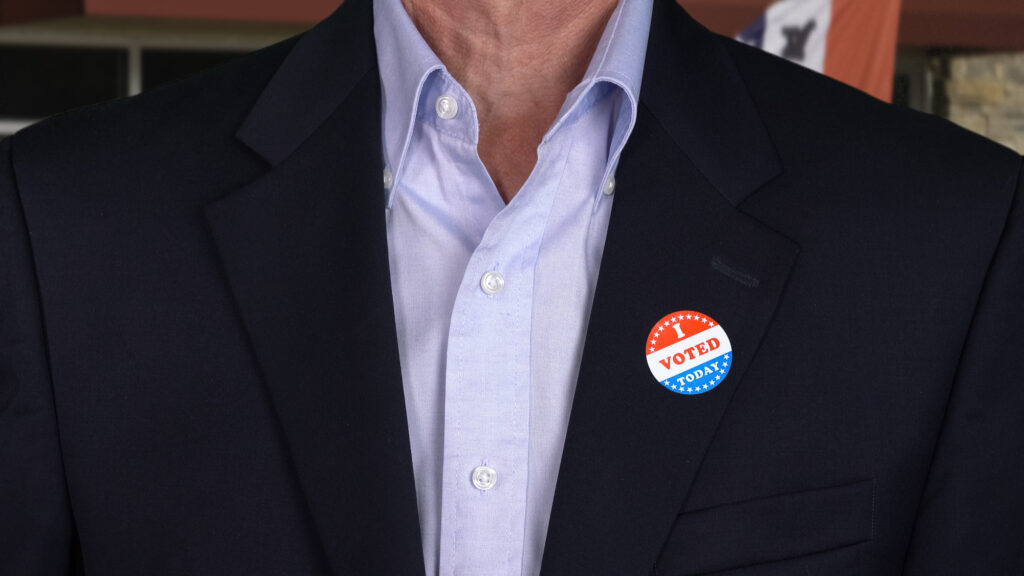 Badge making: I Voted Today badge button on the shirt of a formally dressed senior man for midterm elections in the USA
