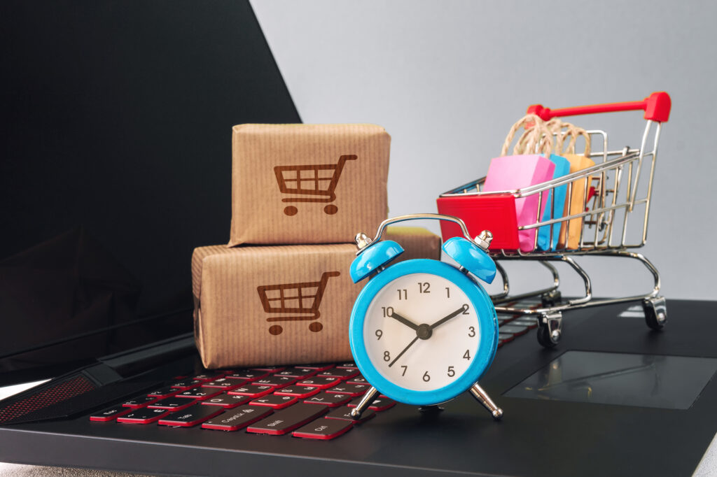 Resist impulse shopping: Paper cartons with a shopping cart or trolley logo on a laptop keyboard, depicts customers order things from retailer sites via the internet.