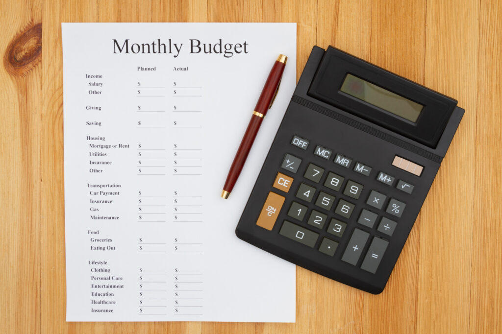 Creating your monthly budget with a calculator with a display and pen on wooden desk