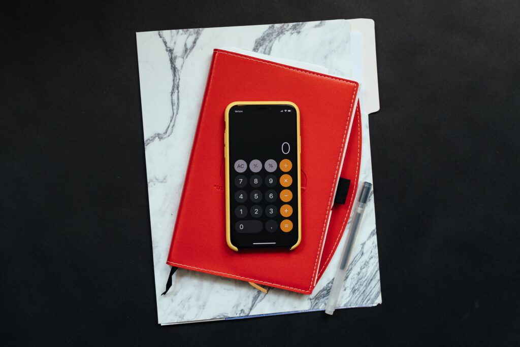 iphone with yellow phoen case laying on top of red portfolio and accounting folder