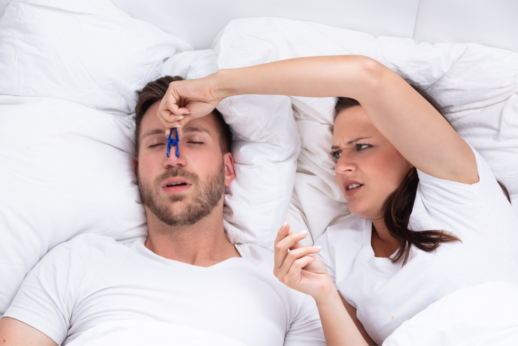 woman plugging the nose of a snoring male partner