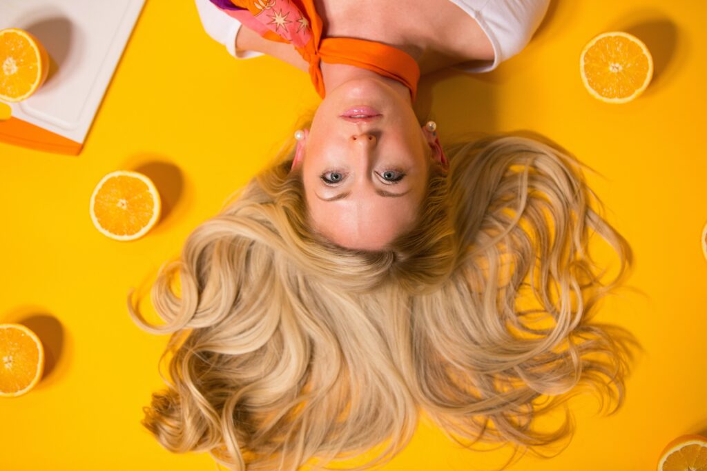 blonde woman laying upside down on yellow background with lemons
