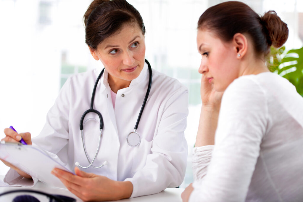 A compassionate doctor consults with a concerned female patient about her CareCredit options during a medical appointment.