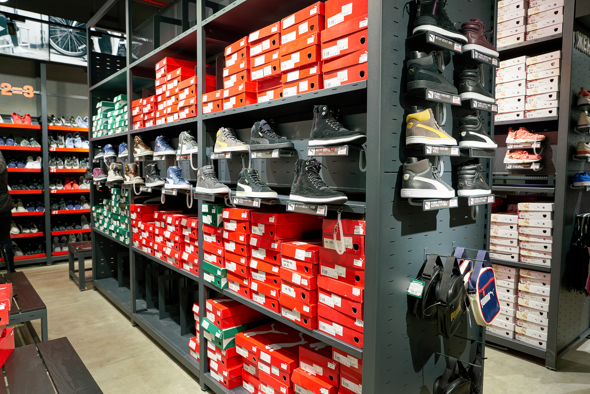Rows of Nike sneakers displayed on shelves in a shoe store with stacks of shoeboxes lining the wall.