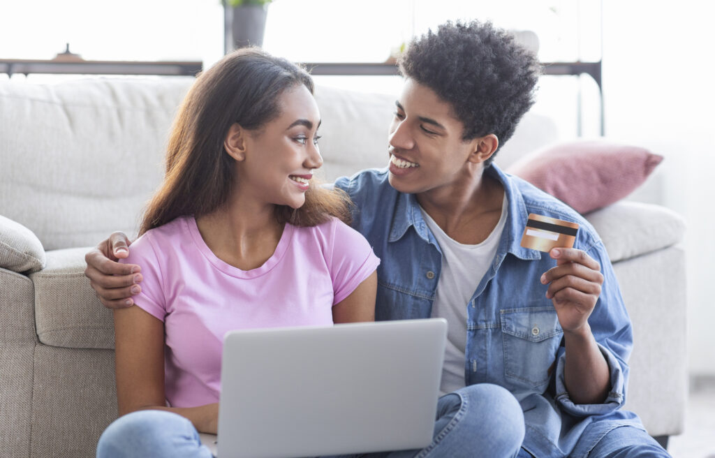 Young african american couple shopping online, using laptop and credit card