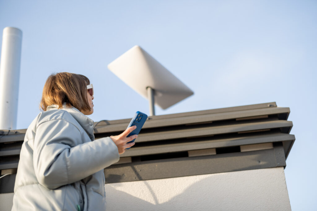 Woman installing Starlink internet satellite dish on roof of her house