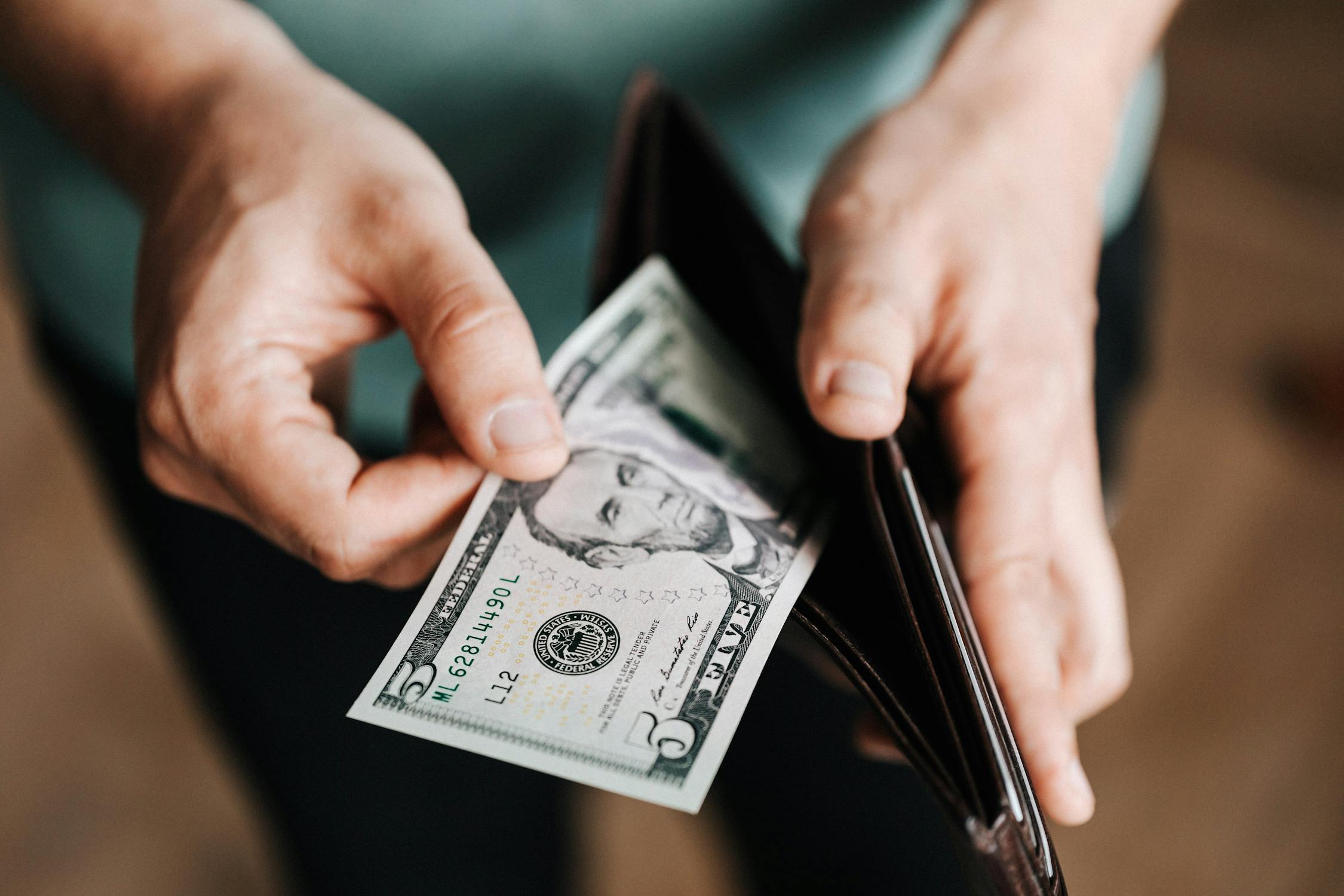 A person taking a US dollar bill out of his wallet.