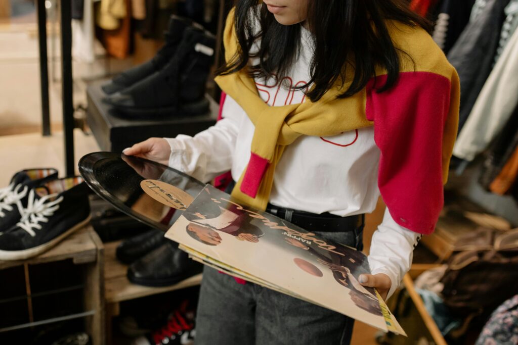 Woman browsing through vinyl records in a vintage clothing store.