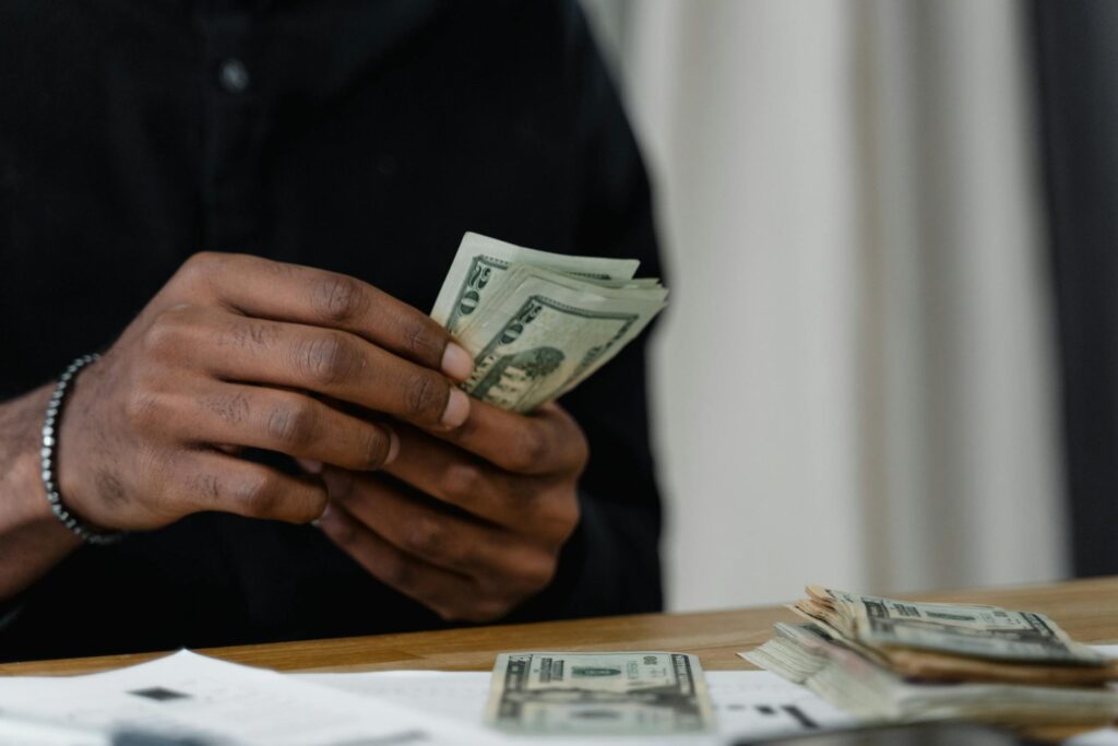 A man in a black shirt counting dollar bills