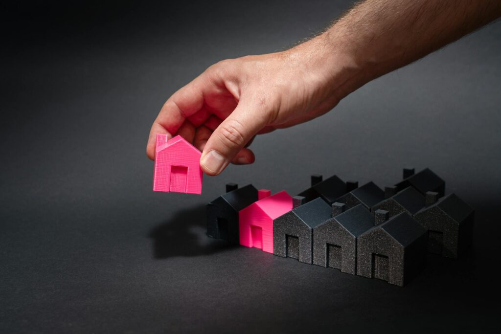 Man picking up and holding miniature houses