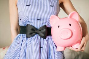 woman in striped desk holding a piggy bank