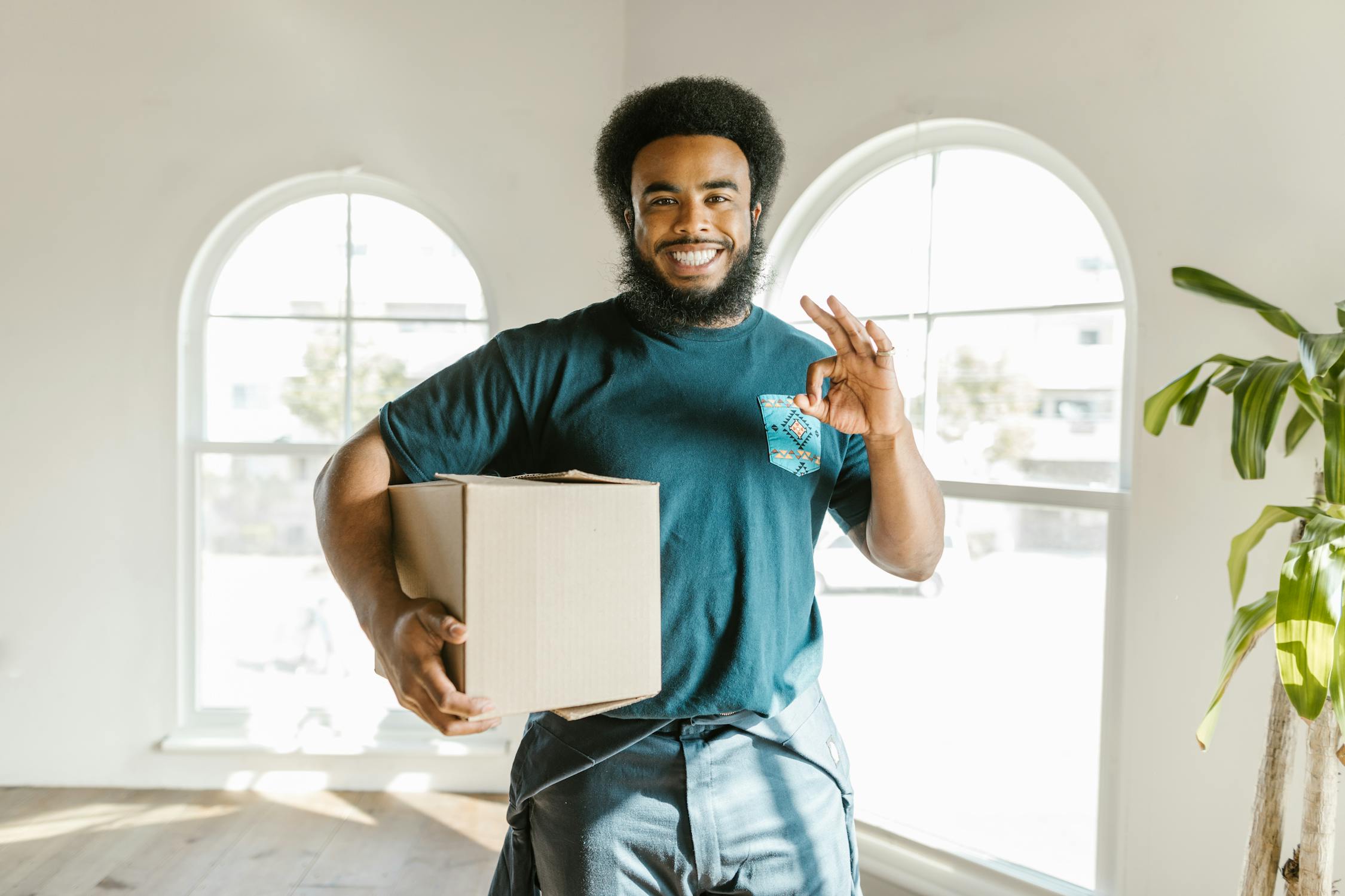 Professional mover holding a box while making the OK sign