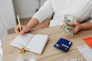 woman holding cash dollar bills while writing down purchase using the 3-day-rule