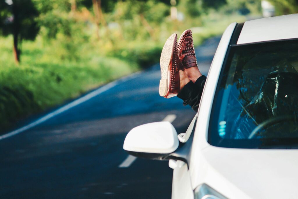 A person in a car with their feet held up out of the window.