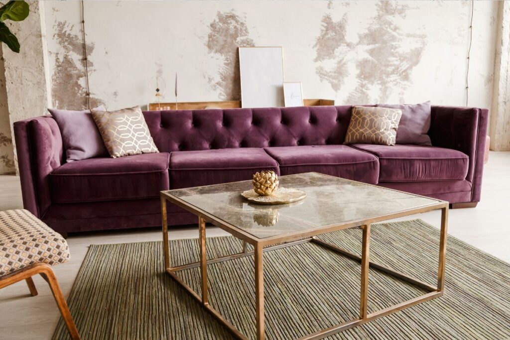 purple sofa with gold coffee table and green plant in background