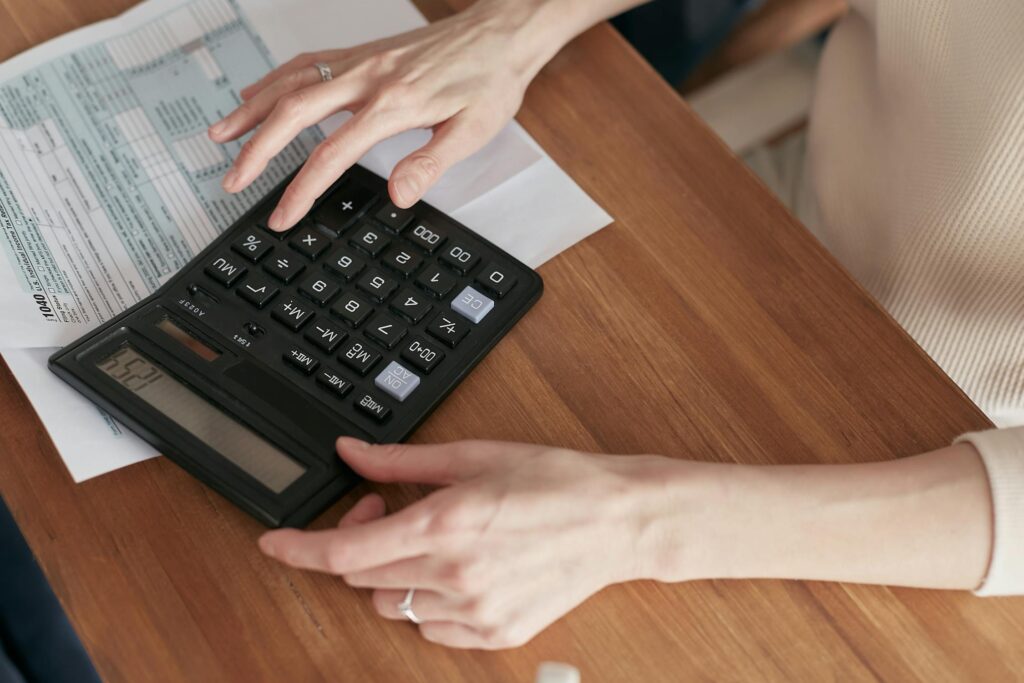 A woman using a calculator on a wooden surface.