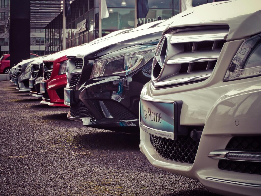 A row of luxury Mercedes-Benz cars parked outside a dealership, showcasing their sleek designs and prominent front grilles.