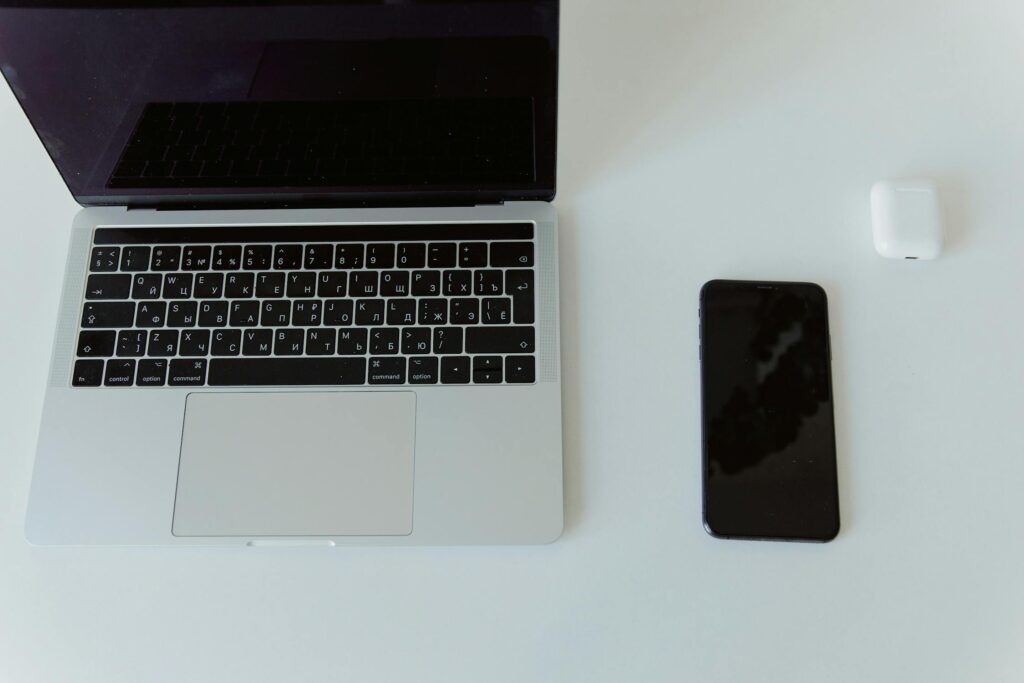 Used MacBook, iPhone, and AirPods placed on a white surface, ready to be sold for cash on Gazelle.