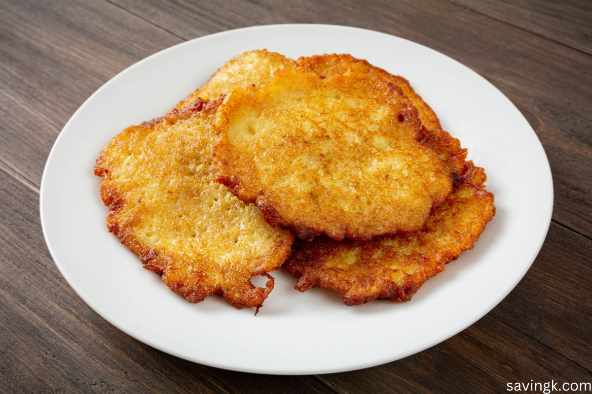 Golden-brown, crispy potato pancakes served on a white plate over a rustic wooden table.