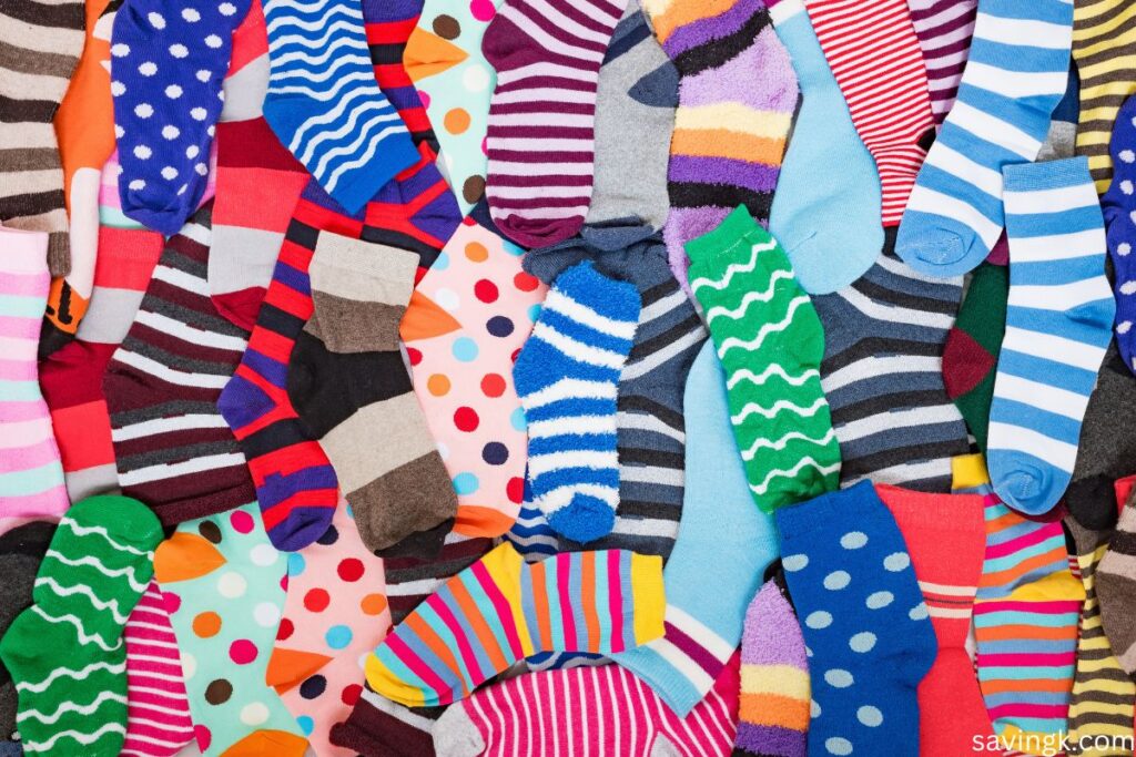 A colorful assortment of mismatched socks in various patterns, including stripes, polka dots, and waves, spread out in a random arrangement.