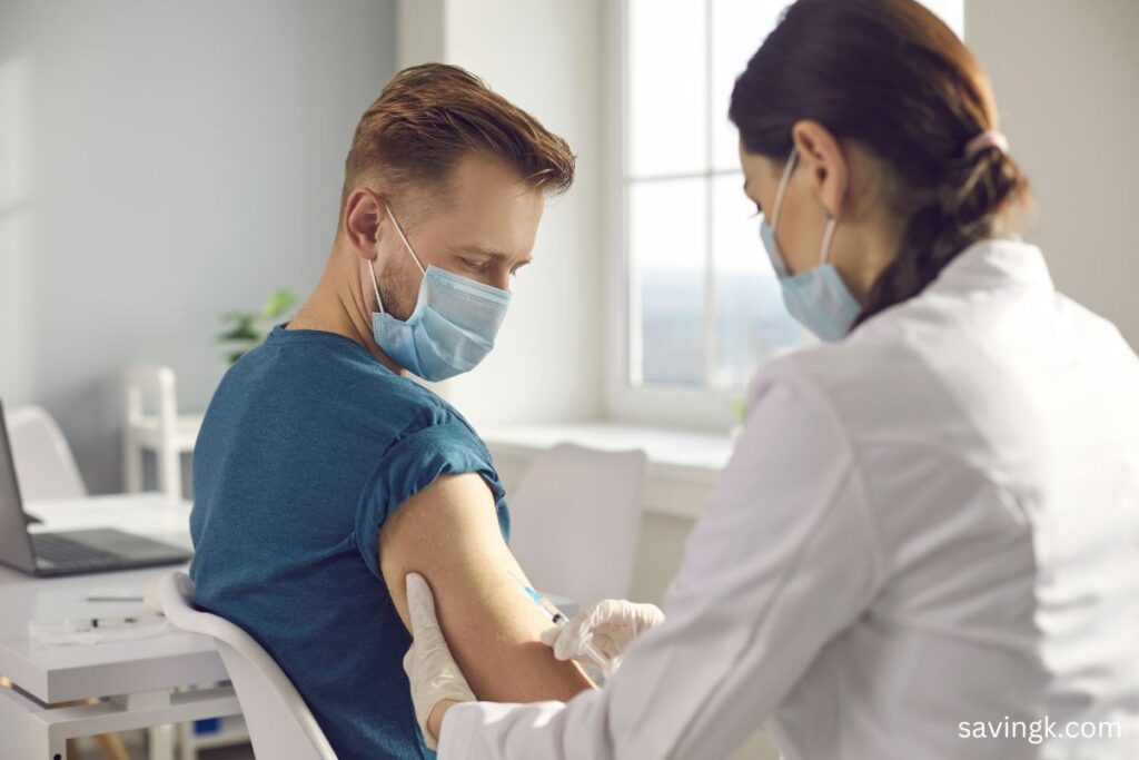 A masked healthcare professional administers an injection to a masked male participant in a clinical trial at a research facility.