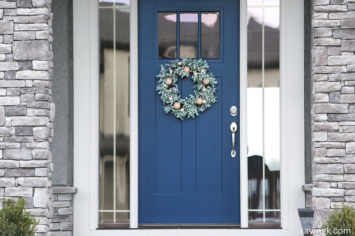 Navy blue front door with a wreath, surrounded by stone walls—symbolizing trust, stability, and the flow of wealth.