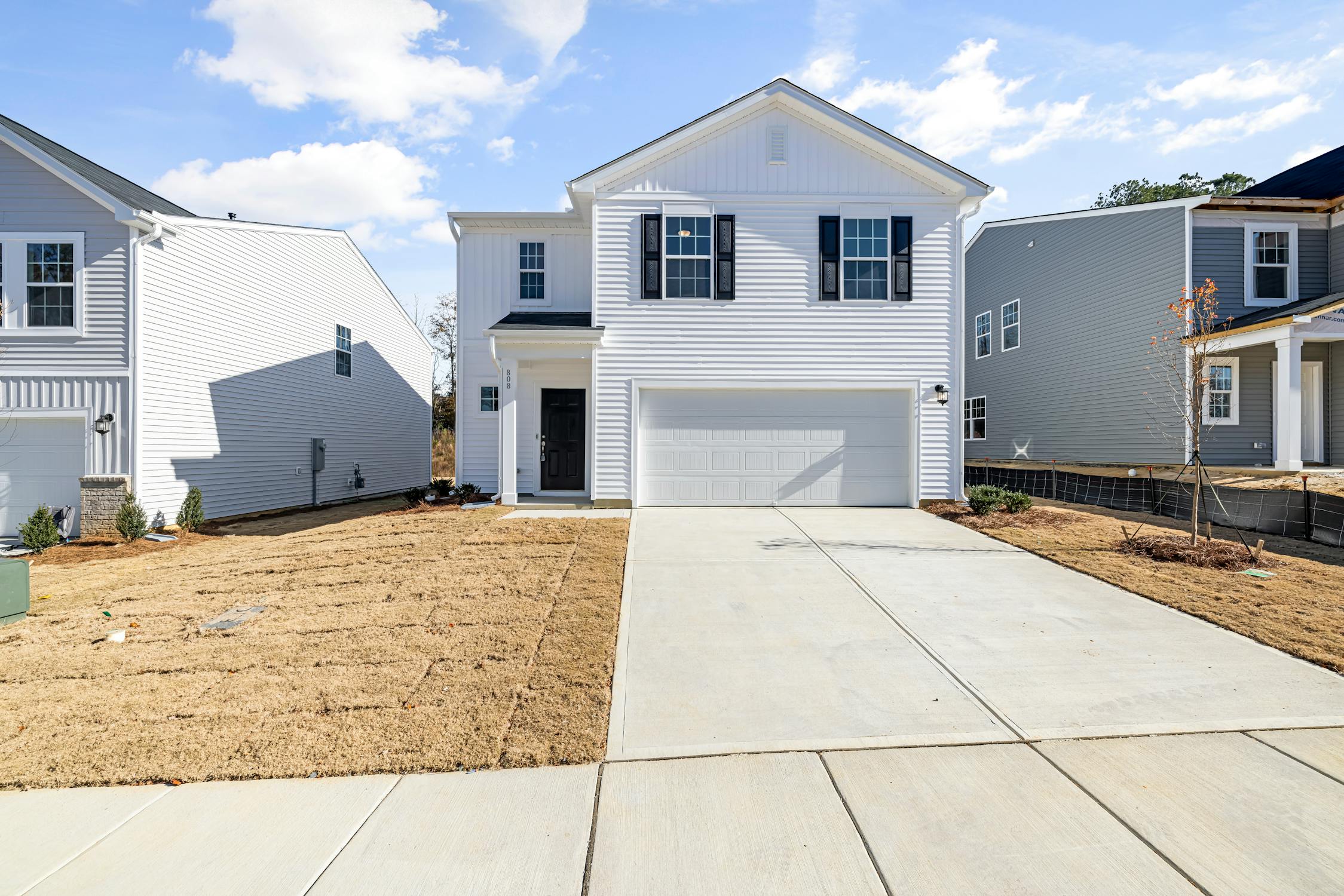 A modern white two-story house with a black front door and a spacious driveway, symbolizing financial stability and career success in Feng Shui.