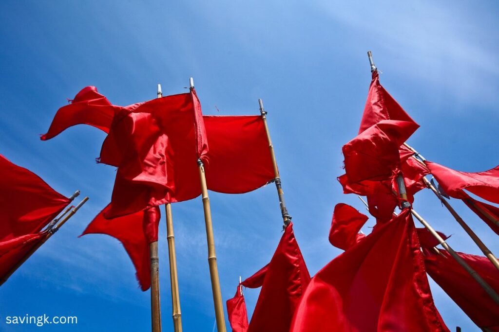 A group of red flags waving against a bright blue sky, symbolizing warning signs to watch for in a financial advisor.