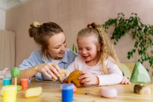Mother and daughter smiling and playing with wooden toys at a table.