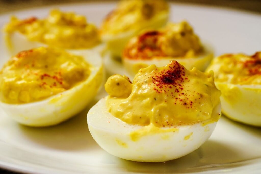 Close-up of creamy deviled eggs sprinkled with paprika on a white plate.
