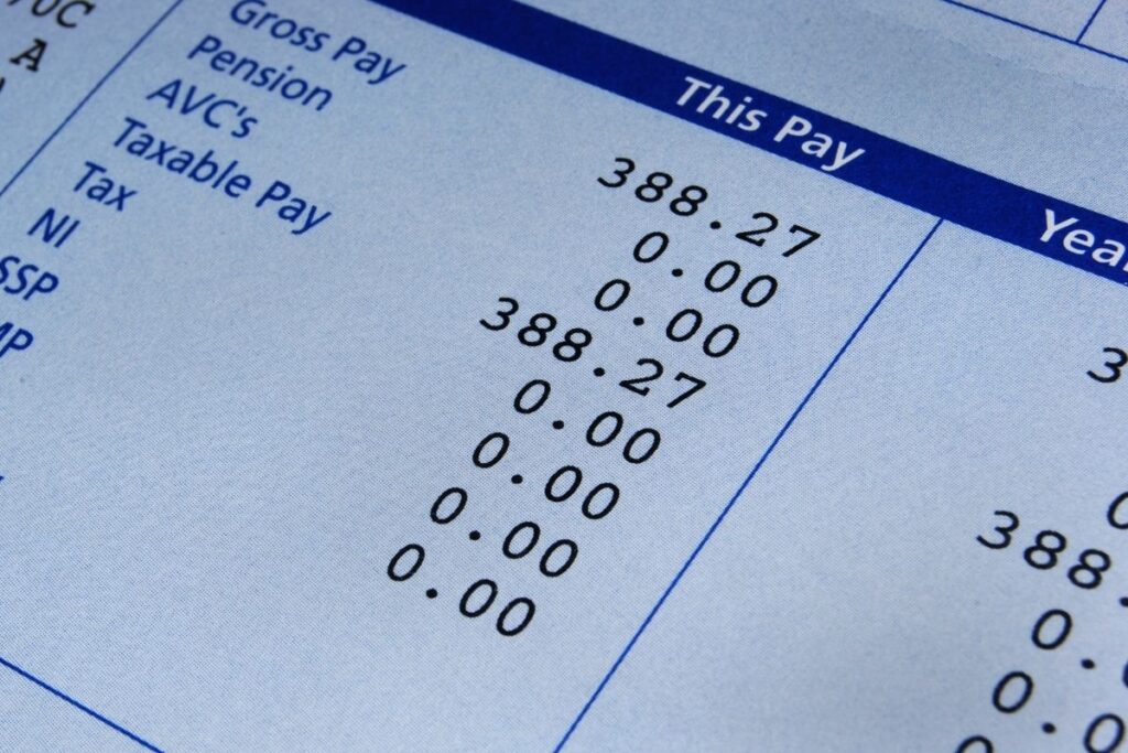 Close-up of a printed paycheck showing gross pay, deductions, and net pay for an employee.