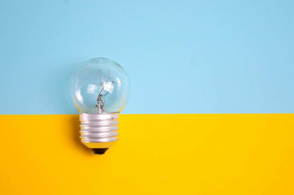 Clear light bulb resting on a split yellow and blue background