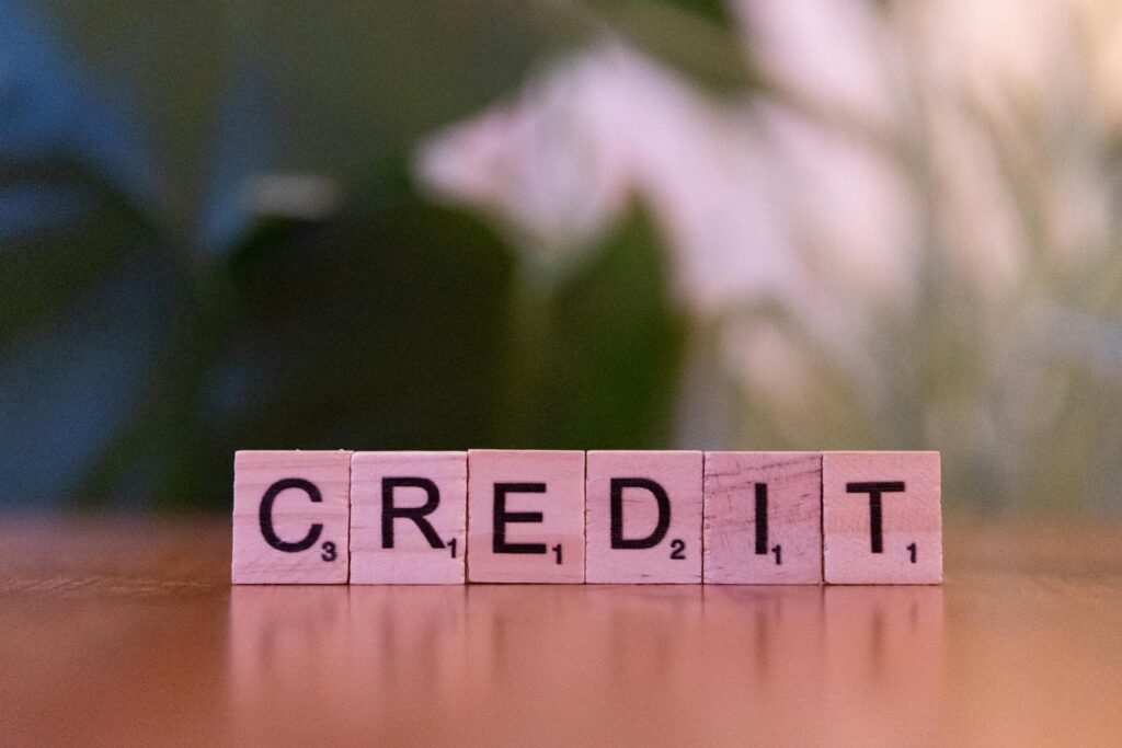 Wooden letter tiles spelling out the word "CREDIT" on a table with a blurred background