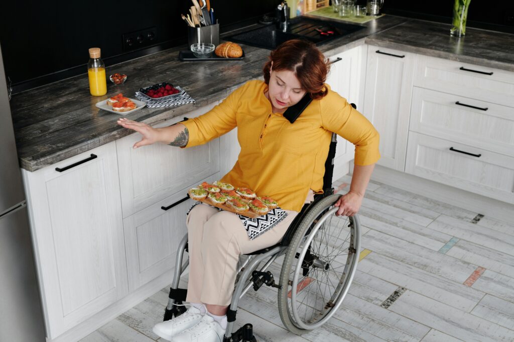 Woman in a wheelchair preparing food independently in her kitchen while talking on the phone.