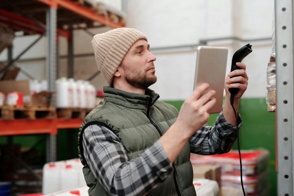 Warehouse worker scanning inventory with a barcode scanner and tablet.