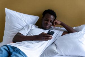 Man relaxing on bed while using smartphone