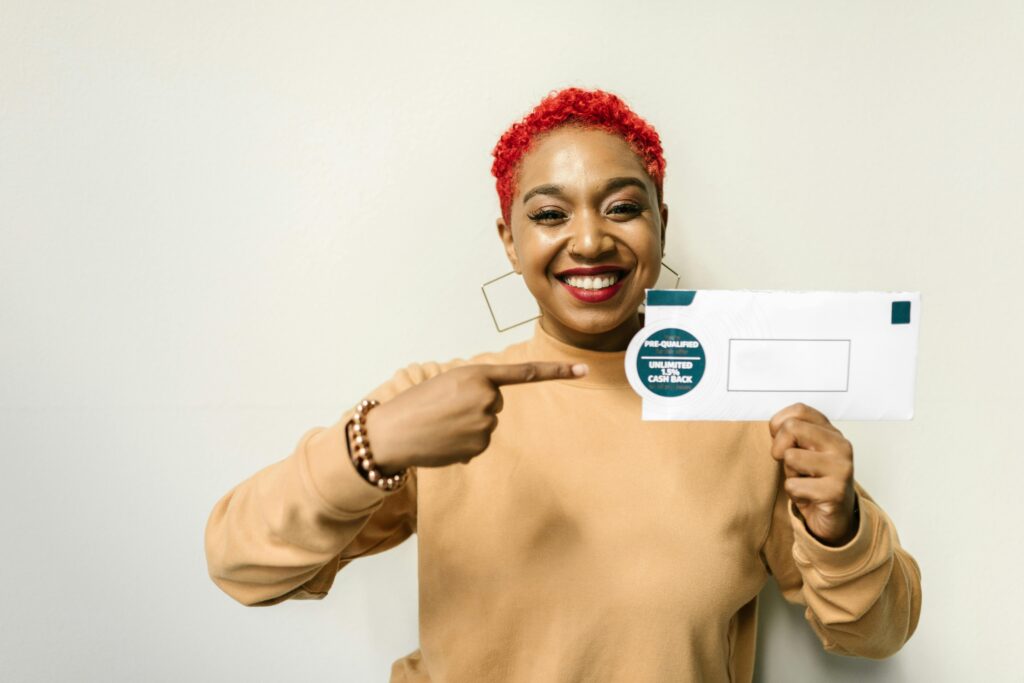 Smiling woman holding and pointing to a cashback offer envelope labeled “Unlimited 1.5% Cash Back”