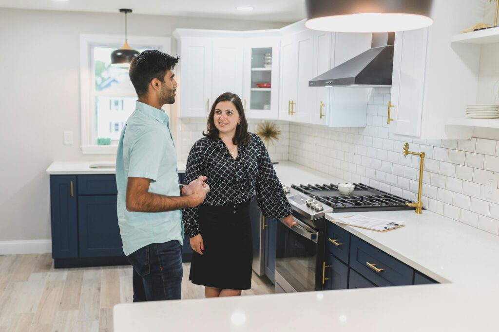 A man and woman discussing kitchen appliances in a modern, upscale kitchen—possibly evaluating a big purchase or renovation.