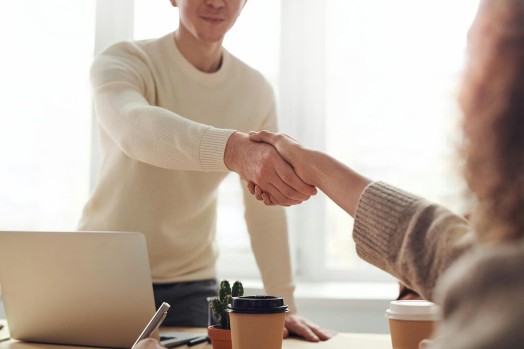 Two people shaking hands across a desk, symbolizing a successful meeting or new opportunity.