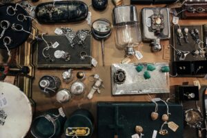 Assorted vintage and antique jewelry, silverware, and decorative items with price tags displayed for sale at an estate sale.