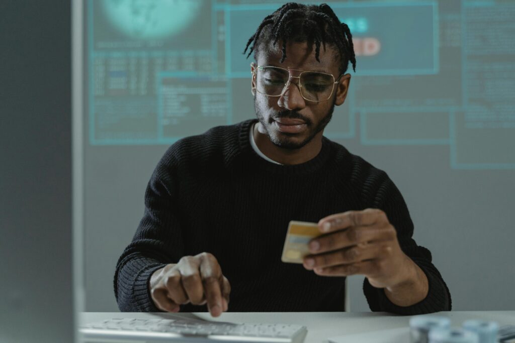 Man holding a credit card while using a computer, symbolizing online security risks and the importance of identity theft protection.