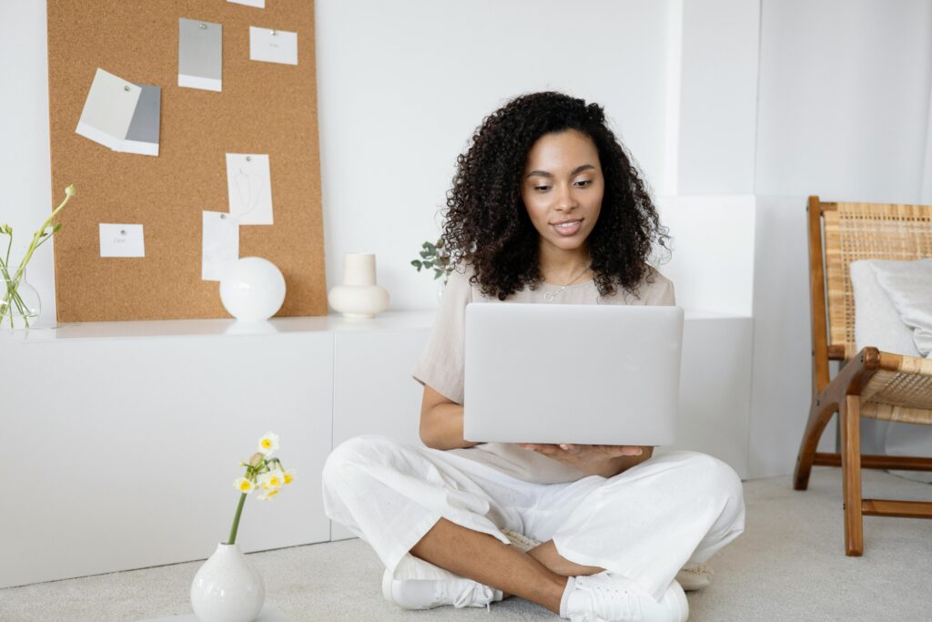 Woman sitting on the floor with a laptop, working on starting a small business from home.