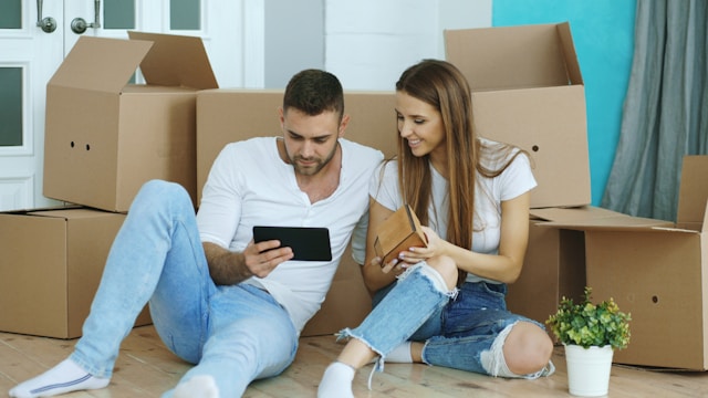 Couple looking at tablet with cardboard boxes behind them