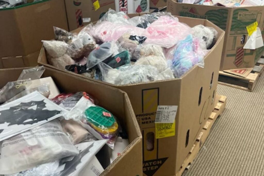 Cardboard bin filled with assorted returned merchandise at a liquidation bin store.