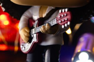 Close-up of a Funko Pop collectible figure holding a red guitar, representing quirky investments like toys and pop culture memorabilia.