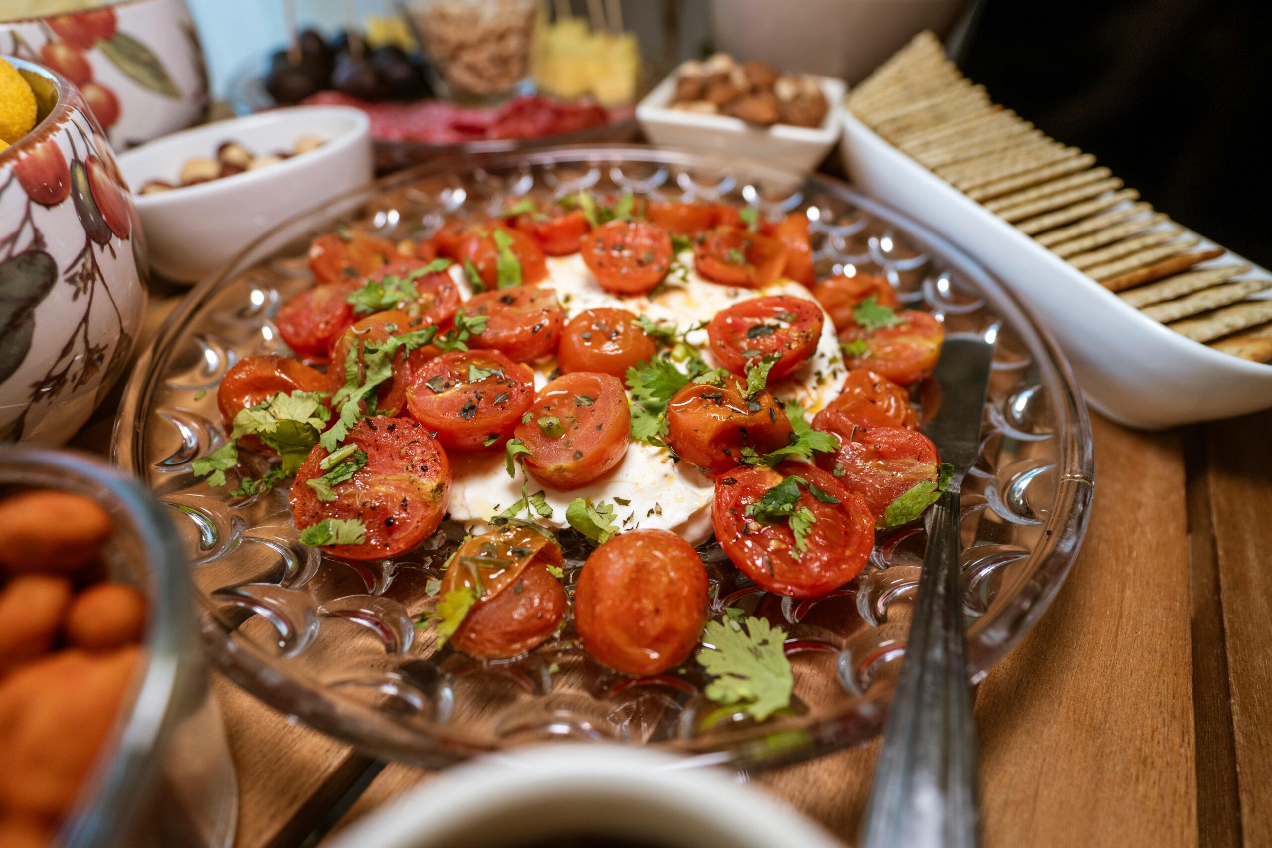 Fresh caprese-style dish with cherry tomatoes, herbs, and mozzarella served with crackers on the side.
