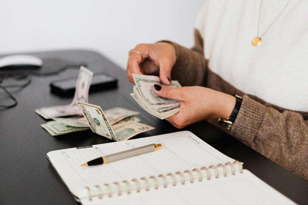 A person budgeting with cash and a planner on a desk